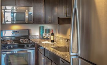 A kitchen with a stove, microwave, and refrigerator.